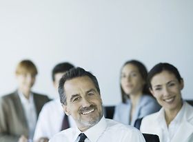 Lächelnder Mann im Vordergrund, Team dahinter