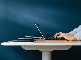 Laptop auf dem Tisch mit tippenden Händen