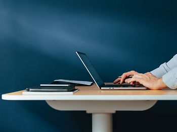 Laptop auf dem Tisch mit tippenden Händen