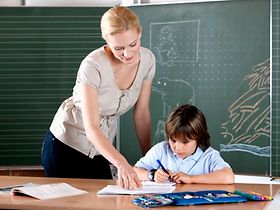 Lehrerin und Schüler vor Tafel