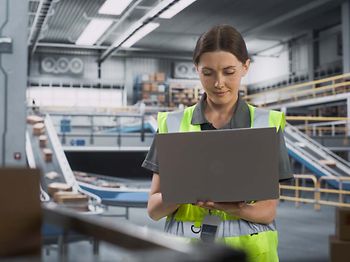 Logistik_Frau mit Laptop vor Paketband