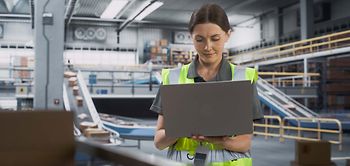 Logistik_Frau mit Laptop vor Paketband