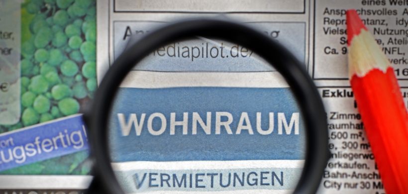 Lupe und Rotstift über der Zeitungsrubrik Wohnungen