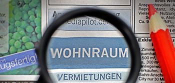 Lupe und Rotstift über der Zeitungsrubrik Wohnungen