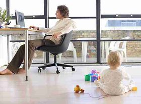 Man using computer by window in home office, side view, baby girl