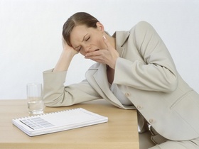 Managerin sitzt muede und gaehnend am Schreibtisch