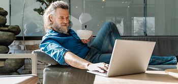 Manm auf Sofa mit Laptop