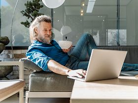 Manm auf Sofa mit Laptop
