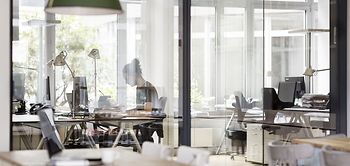 Mann arbeitet im modernen Büro hinter einer Glaswand
