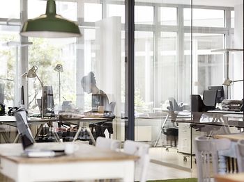 Mann arbeitet im modernen Büro hinter einer Glaswand