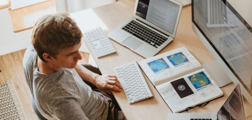 Mann arbeitet mit mehreren Bildschirmen im Homeoffice