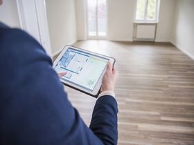 Mann benutzt Tablet in leerer Wohnung