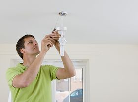 Mann bringt Energiesparlampe an Decke an