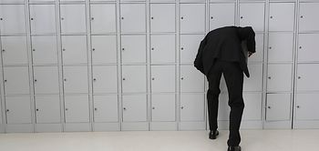 Mann bückt sich vor Schließfächern