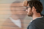 Shot of a thoughtful young entrepreneur leaning against a glass window in his office