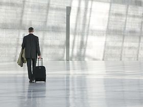 Mann geht mit Trolley-Koffer durch große Halle