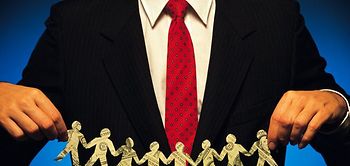 Mann hält Kette aus Papiermännchen aus Dollarscheinen in den Händ