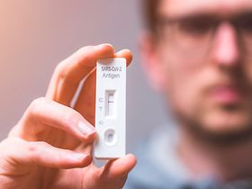 Mann hält negativen Coronatest in der Hand