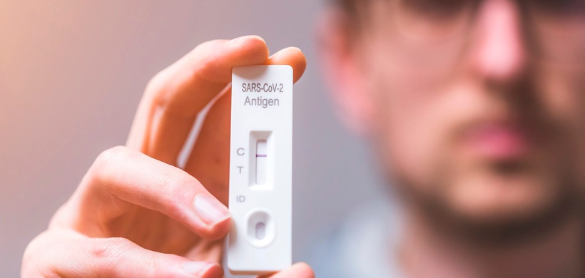 Close up of young man holding express antigen covid test, negative result