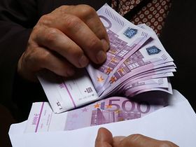 Mann holt 500er Geldscheine aus Briefumschlag