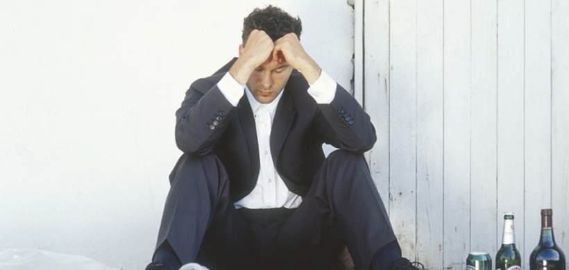 Mann im Anzug sitzt depressiv am Boden