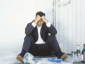 Mann im Anzug sitzt depressiv am Boden