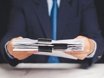 mann im anzug uebergibt aktenpaket