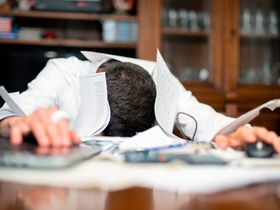 Mann im Büro, verzweifelt, Blätter überall