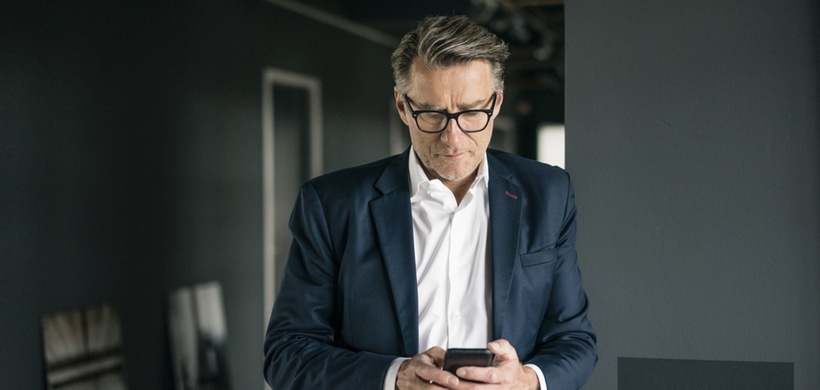 Mann in Anzug guckt auf Handy