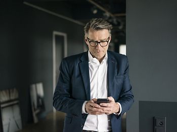 Mann in Anzug guckt auf Handy