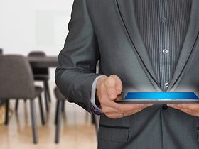 Mann in Anzug mit Tablet vor leerem Konferenzraum