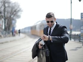 Mann in Anzug schaut fluchend auf seine Uhr