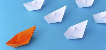 Weiße Papierschiffchen, ein rotes Schiff aus Papier