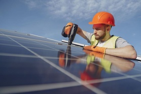 Mann installiert Photovoltaik auf Dach, Solarstrom