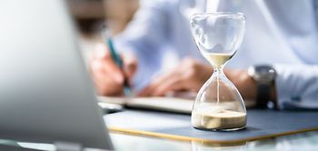 Mann Laptop Schreibtisch Stundenglass Unterlagen