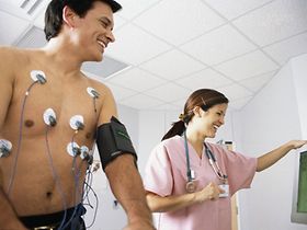 Mann macht EKG, Krankenschwester steht daneben