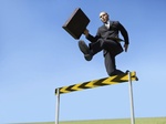 Mann mit Aktenkoffer springt über Hürde