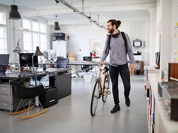 Mann mit Fahrrad im Büro