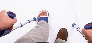 Mann mit Gehstützen und Gips