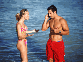 Mann mit Handy und Frau am Strand