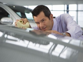 Mann mit Hemd poliert Auto