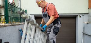 Mann mit Leiter vor Garage
