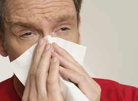 Mann putzt sich die Nase