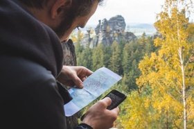 Mann mit Smartphone und Karte in Natur
