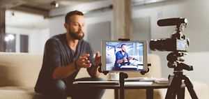 mann produziert videoinhalt mit kamera und tablet