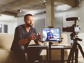 mann produziert videoinhalt mit kamera und tablet
