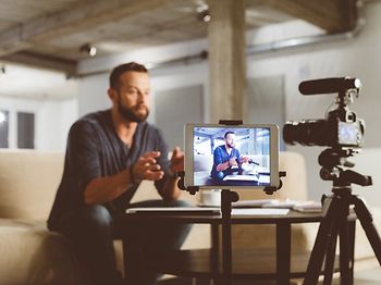 mann produziert videoinhalt mit kamera und tablet