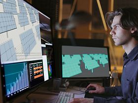 Mann schaut auf Bildschirm mit Solarpanels und Charts