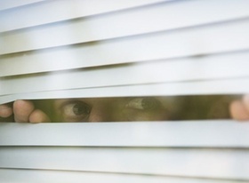 Man looks thru window blinds