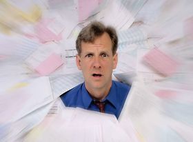 Mann schaut erschreckt gestresst aus Papierstapel